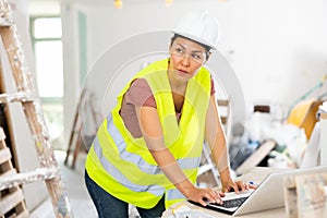 Woman builder using laptop in construction site