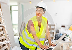 Woman builder using laptop in construction site