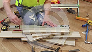 Woman Builder using spirit level and marking with pencil