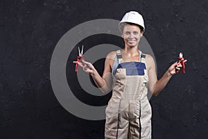 Woman builder worker in uniform holds wirecutter. Electrician female in helmet. Professional electric engineer. photo