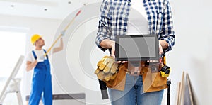 Woman builder with working tools showing tablet pc