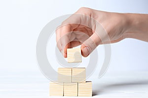 Woman building pyramid of cubes on white background, closeup with space for text. Idea concept
