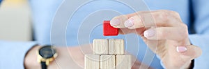 Woman building pyramid from wooden cubes closeup