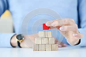 Woman building pyramid from wooden cubes closeup