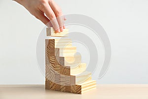 Woman building steps with wooden blocks at table. Career promotion concept