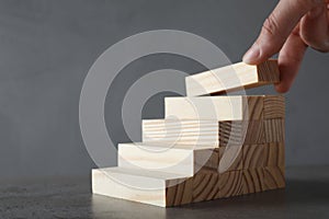 Woman building steps with wooden blocks on table, closeup. Career ladder