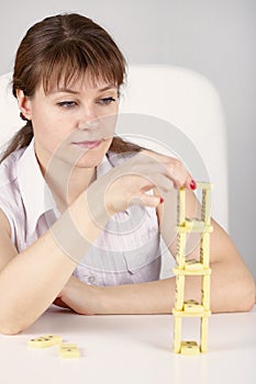 Woman builds precarious tower of dominoes