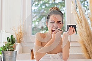 Woman in bun hairsyle with open mouth mustache removing, screaming in pain