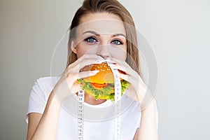 Woman with burger and measuring tape while dieting