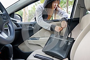 Woman burglar steal a shoulder bag through the window of car - t