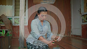 A Woman burning a photo frame with gasoline in front of the house with brown floor