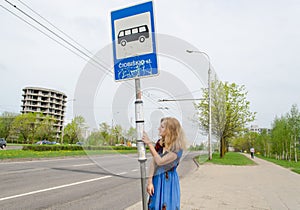 Woman at bus stop with pole tags driving schedules