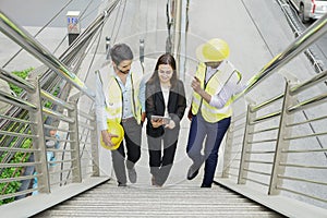 woman business inspector using tablet for discussing with engineers project manager while walking upstair