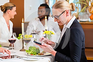 Woman on business lunch checking mails on phone