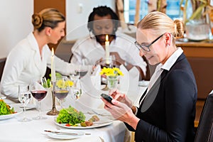 Woman on business lunch checking mails on phone