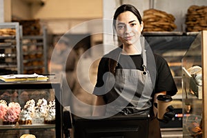 woman business owner with bakery shop background near showcases with pastries