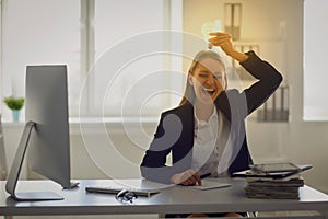 A woman in a business suit holds a glowing lamp in her hands at a table in the office.