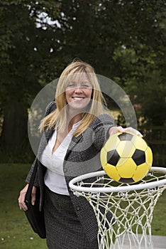 Woman in business suit and netball net scoring a goal