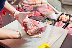 Woman in butcher shop selling meat fillet