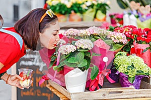 Woman buyer selects and smells bouquets before buying at a flower shop on the street