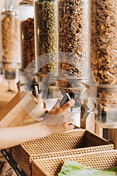 Woman buying cereals and grains in sustainable plastic free grocery shop.