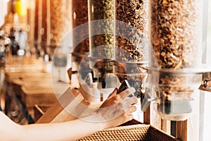 Woman buying cereals and grains in sustainable plastic free grocery shop.