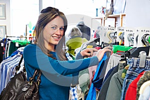 Woman Buying Children's Clothes In Charity Shop