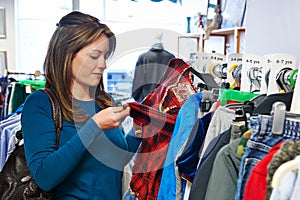 Woman Buying Children's Clothes In Charity Shop