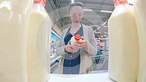 Woman buying fresh milk at supermarket