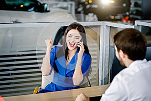 Woman buying a new car talking on smartphone