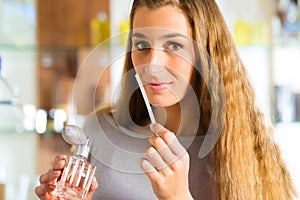 Woman buying perfume in shop or store