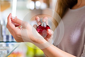 Woman buying perfume in shop or store