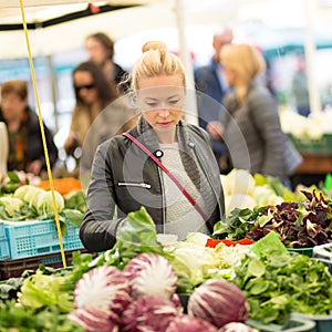 Woman buying vegetable at local food market.