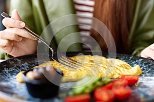 Woman in cafe eating breakfast omelet with vegetables close-up of fork with food, home-cooked food in restaurant, social