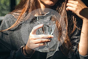 A woman in a cafe holds a glass of water in her hand.