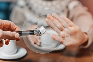 Woman in cafe refuses a piece of white sugar for her tea. Say no to sugar and fast carbs. Diet for diabetes and addiction to