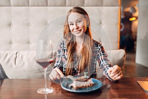 Woman in cafe, sweet cake and wine on the table