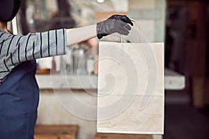 Woman cafe worker serving unrecognizable customer outdoors