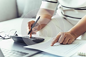 Woman is calculating annual tax with calculator and filling form of Individual Income Tax Return. Season to pay Tax and Budget