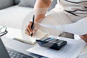 Woman is calculating annual tax, monthly expenses with calculator and filling form of Individual Income Tax Return. Season to pay