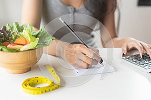 Woman calculating calories in her meal and taking note