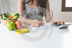 Woman calculating calories in her meal and taking note