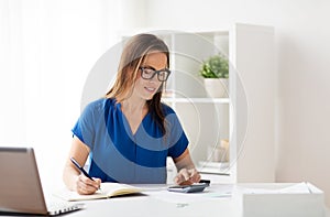 Woman with calculator and notebook at office