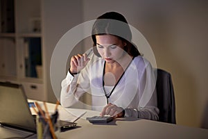 Woman with calculator and papers at night office