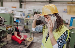 Woman is calling ambulance for her colleague after accident in factory. First aid support on workplace concept.