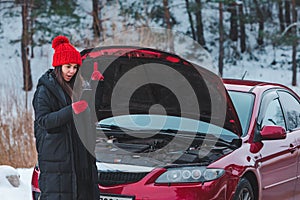 woman calling for help with broken down car at winter highway