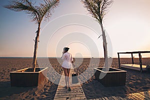 Woman calling by phone and walking on beach.