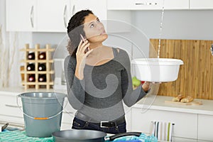 woman calling plumber to fix water leaking from ceiling