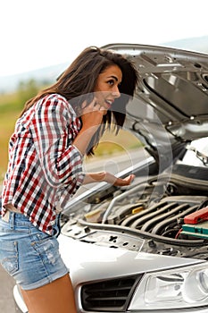 Woman calling service in front of broken car