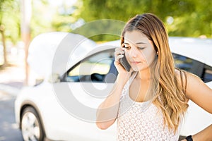 Woman calling someone for help with her broken car